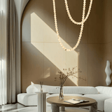 Modern living room with a white sofa, round wooden table, and decorative elements.