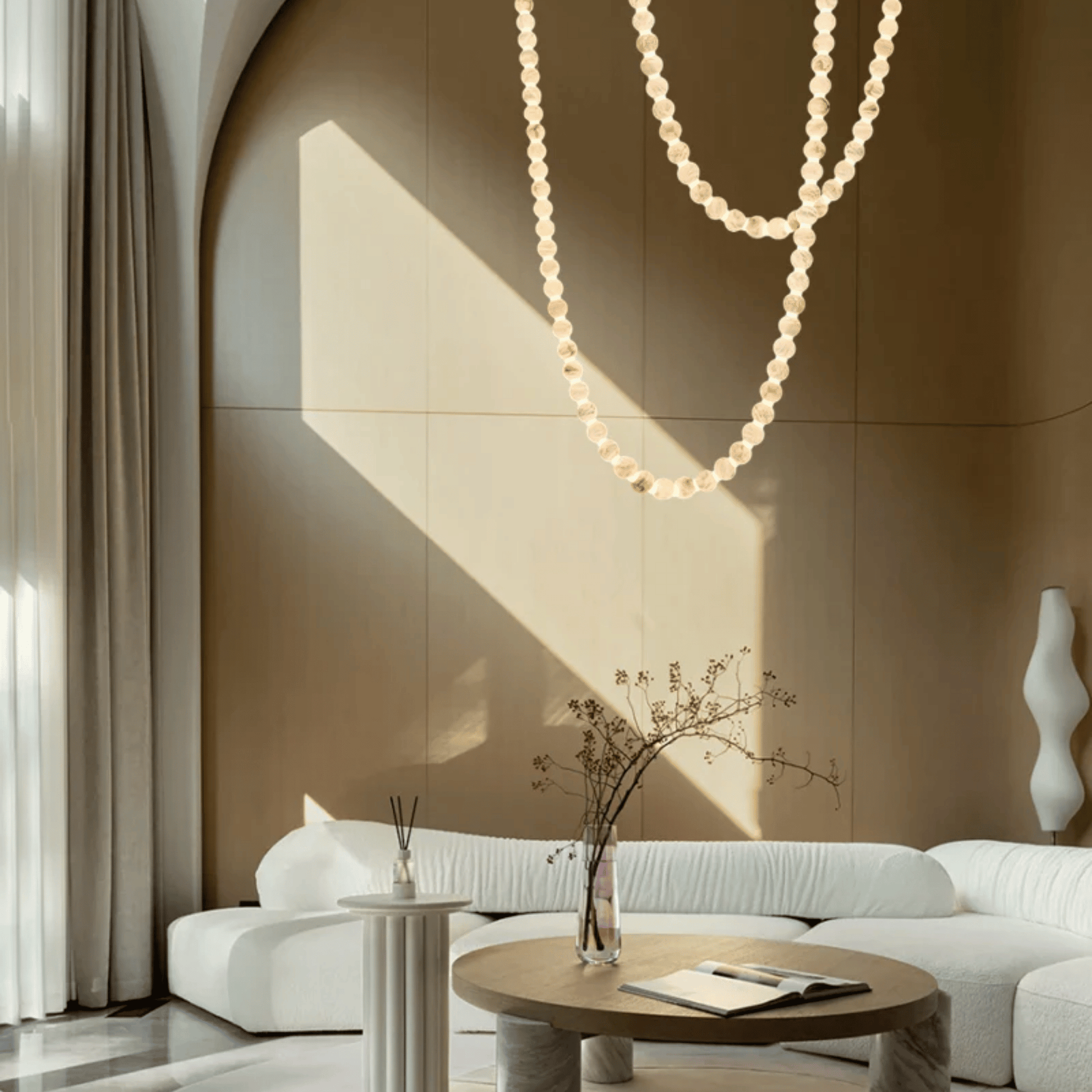 Modern living room with a white sofa, round wooden table, and decorative elements.