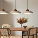 Dining area with wooden table and chairs under three pendant lights.