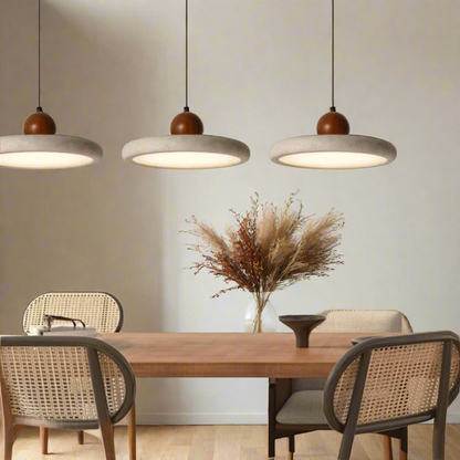 Dining area with wooden table and chairs under three pendant lights.
