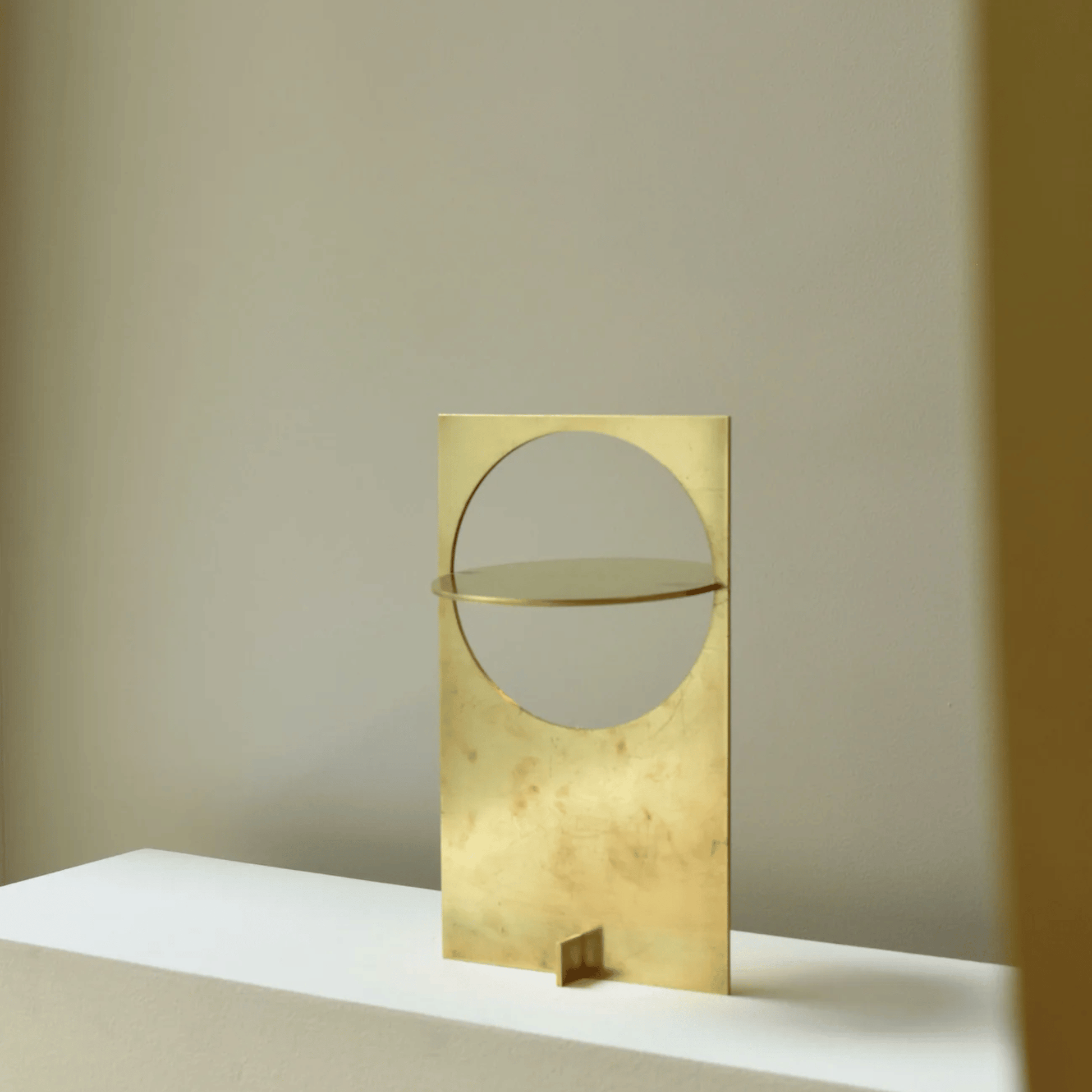 Gold decorative object with circular design on a neutral background