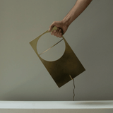 Hand holding a geometric lamp against a plain background