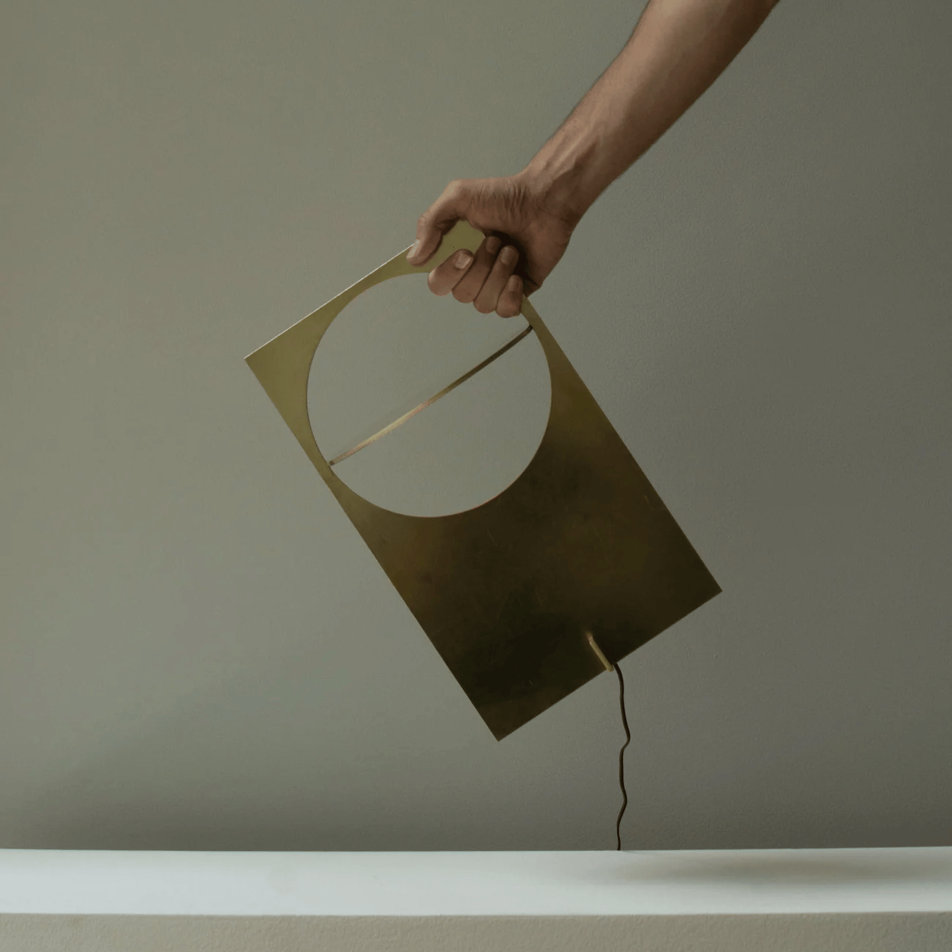 Hand holding a geometric lamp against a plain background