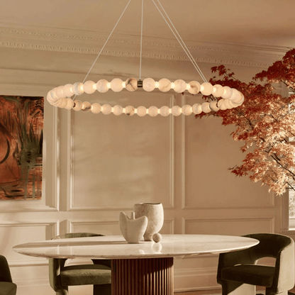 Modern chandelier hanging above a dining table in a stylish room with decor elements.