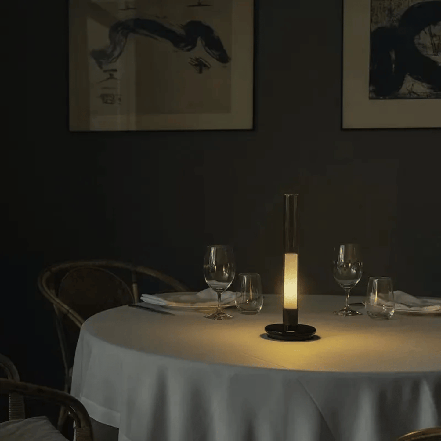Dining table set with glasses and a candle in a dimly lit room.