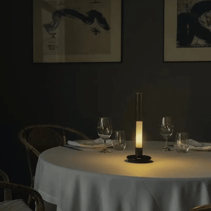 Dining table set with glasses and a candle in a dimly lit room.