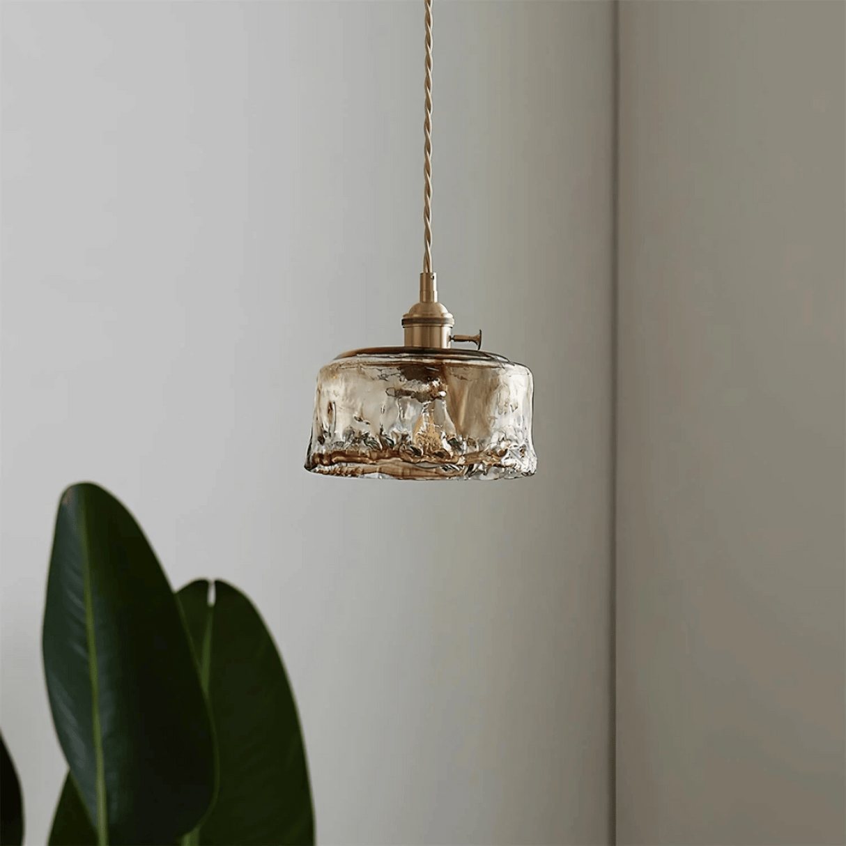 Vintage-style pendant light with glass shade and brass fixture against a neutral wall.