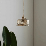 Vintage-style pendant light with glass shade and brass fixture against a neutral wall.