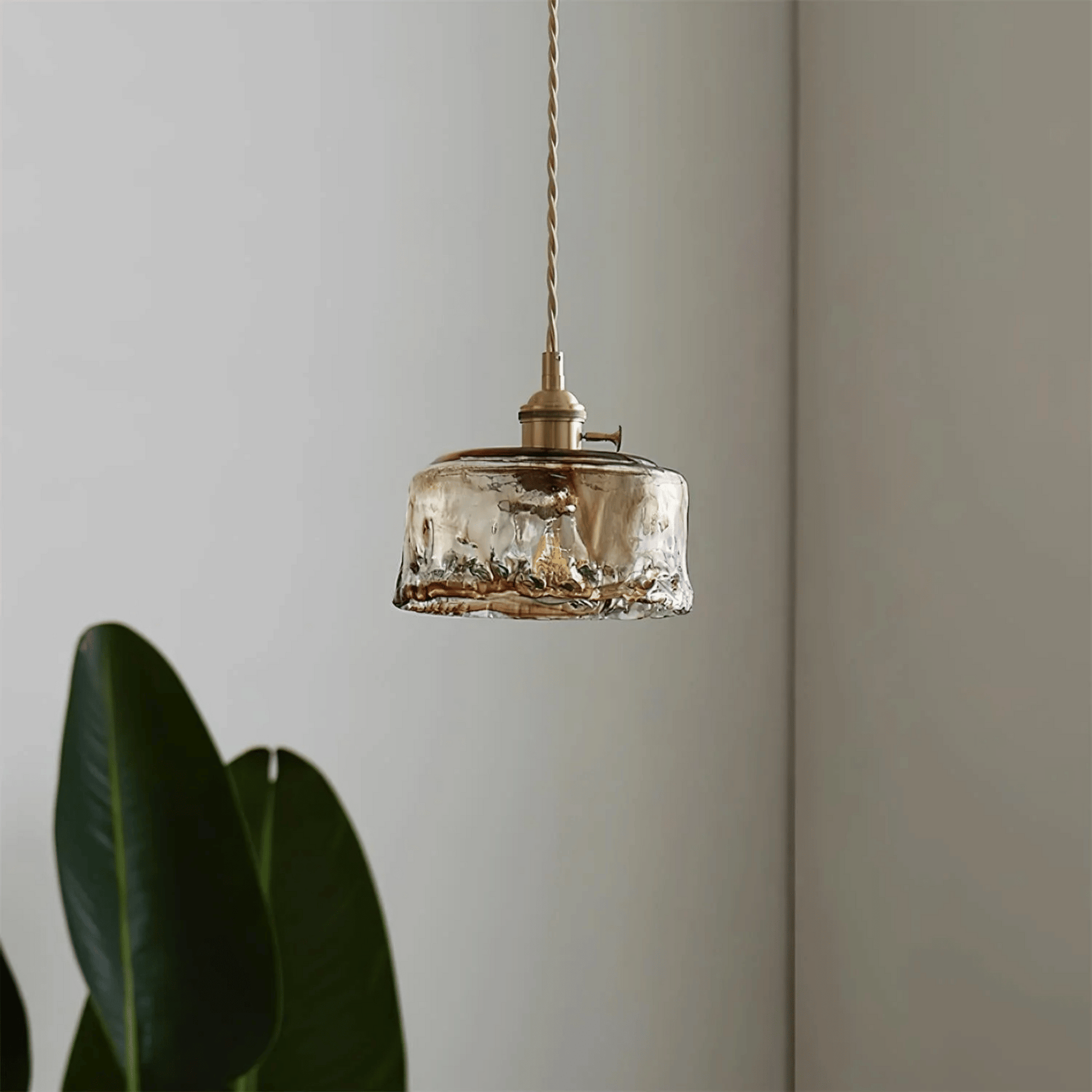 Vintage-style pendant light with glass shade and brass fixture against a neutral wall.