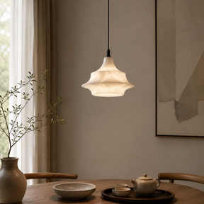 Pendant light hanging above a wooden table with ceramic items and a vase.
