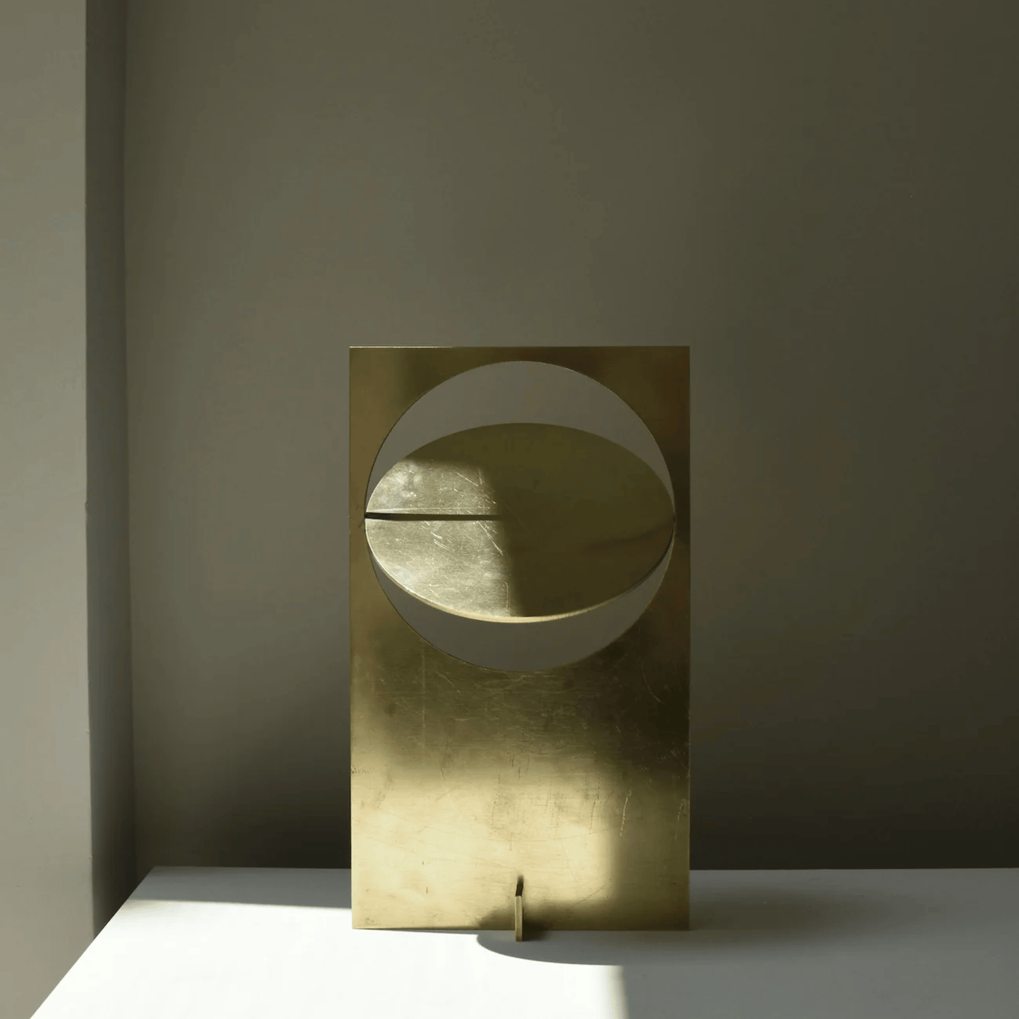 Gold abstract sculpture on a gray surface with a dark background