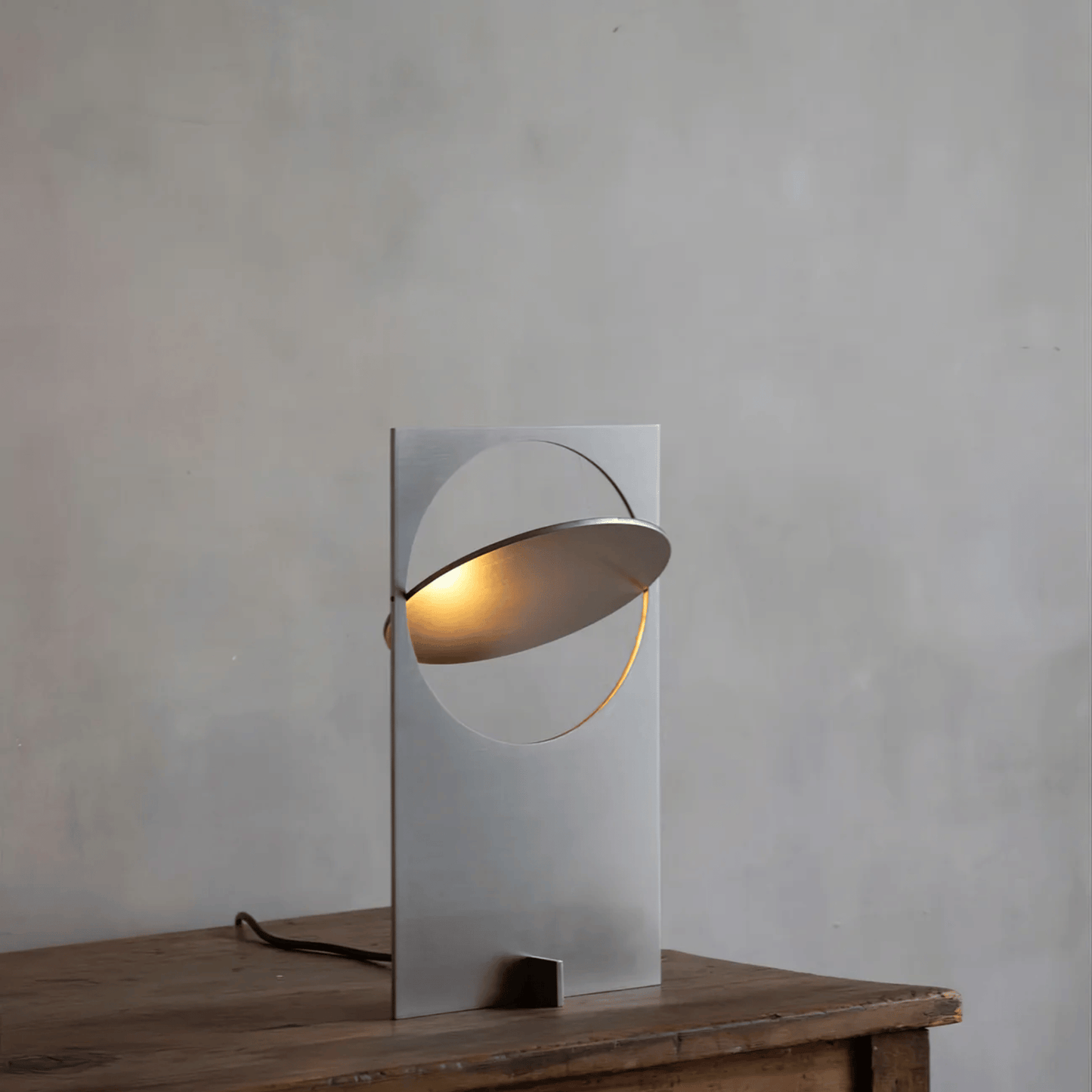 Modern table lamp with a metallic design on a wooden surface against a gray wall