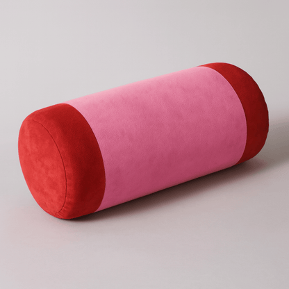 Cylindrical pillow with pink and red color pattern on a light gray background