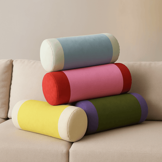 Stack of colorful cylindrical pillows on a beige sofa.