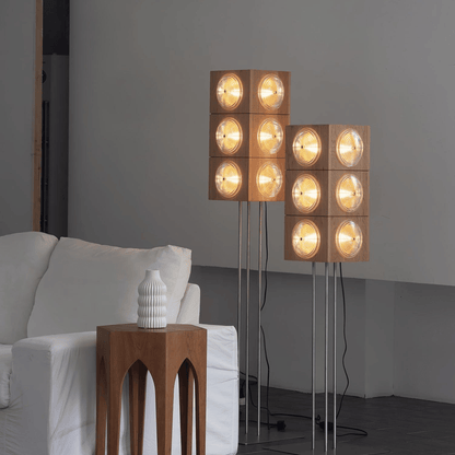 Modern floor lamp with square wooden panels and glass lights in a living room setting.