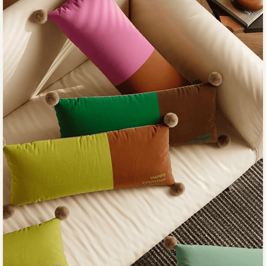 Colorful pillows on a beige sofa with a checkered rug.