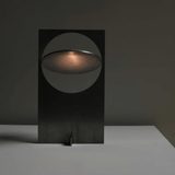 Modern black table lamp with a circular design on a dark background
