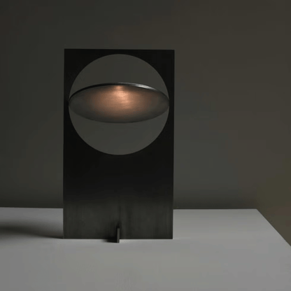 Modern black table lamp with a circular design on a dark background