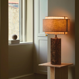 Decorative lamp on a wooden stand in a room with a window.