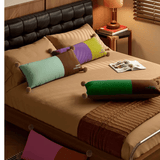 Bed with colorful pillows and a magazine on a wooden nightstand.
