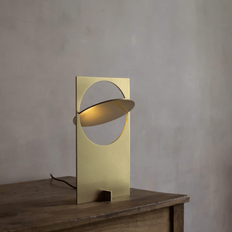 Gold table lamp on a wooden surface with a gray background