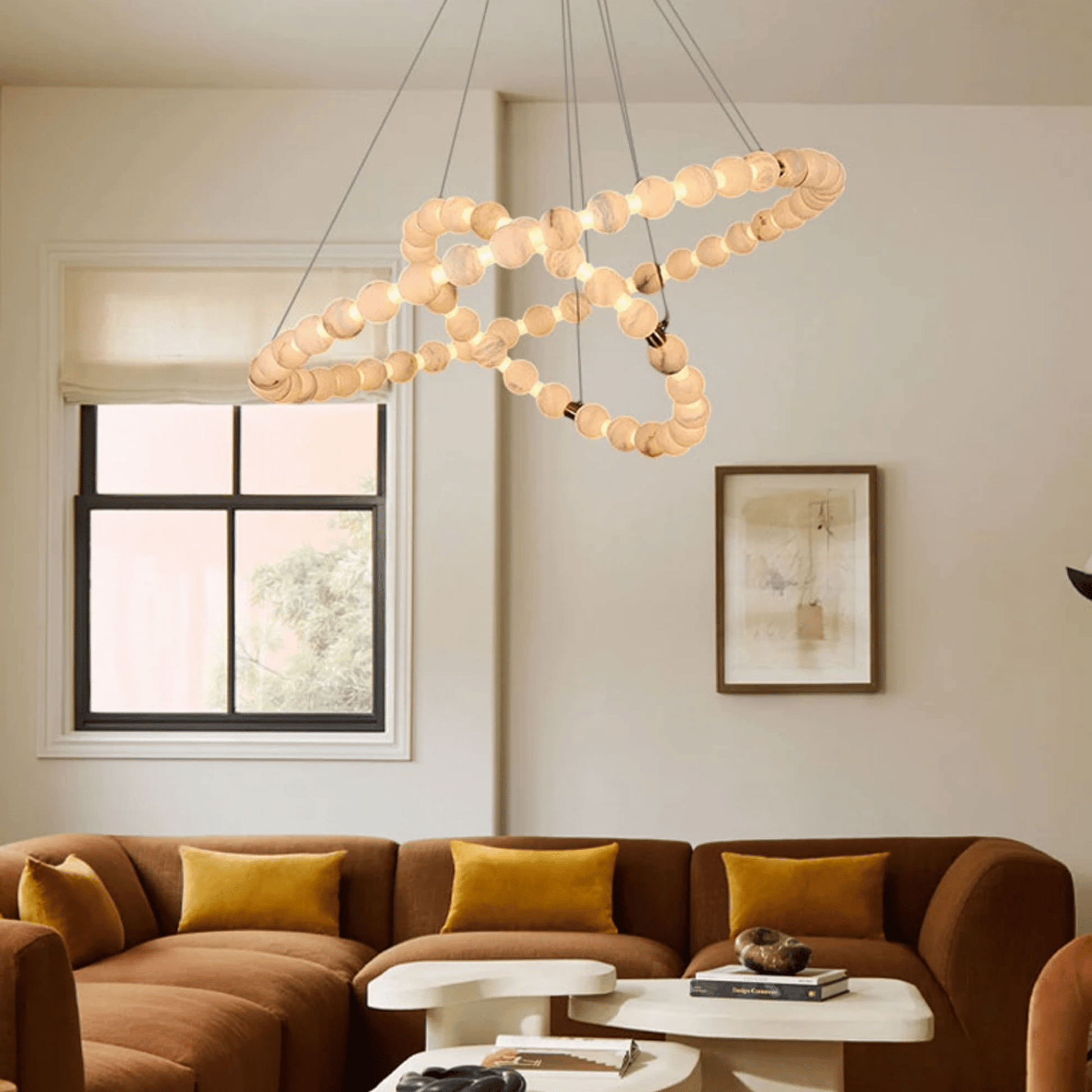 Modern living room with a chandelier, brown sectional sofa, and abstract art on the wall.