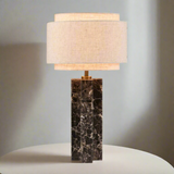 Table lamp with marble base and beige fabric shade on a white background