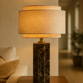 Table lamp with a marble base on a wooden table in a living room setting.