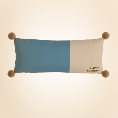 Color-blocked pillow with pom-pom accents and 'Happy Everyday' text on a beige background