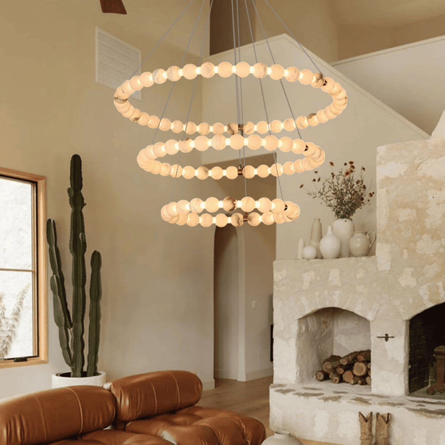 Modern chandelier hanging in a living room with a fireplace and cactus.