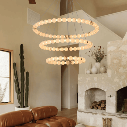 Modern chandelier hanging in a living room with a fireplace and cactus.