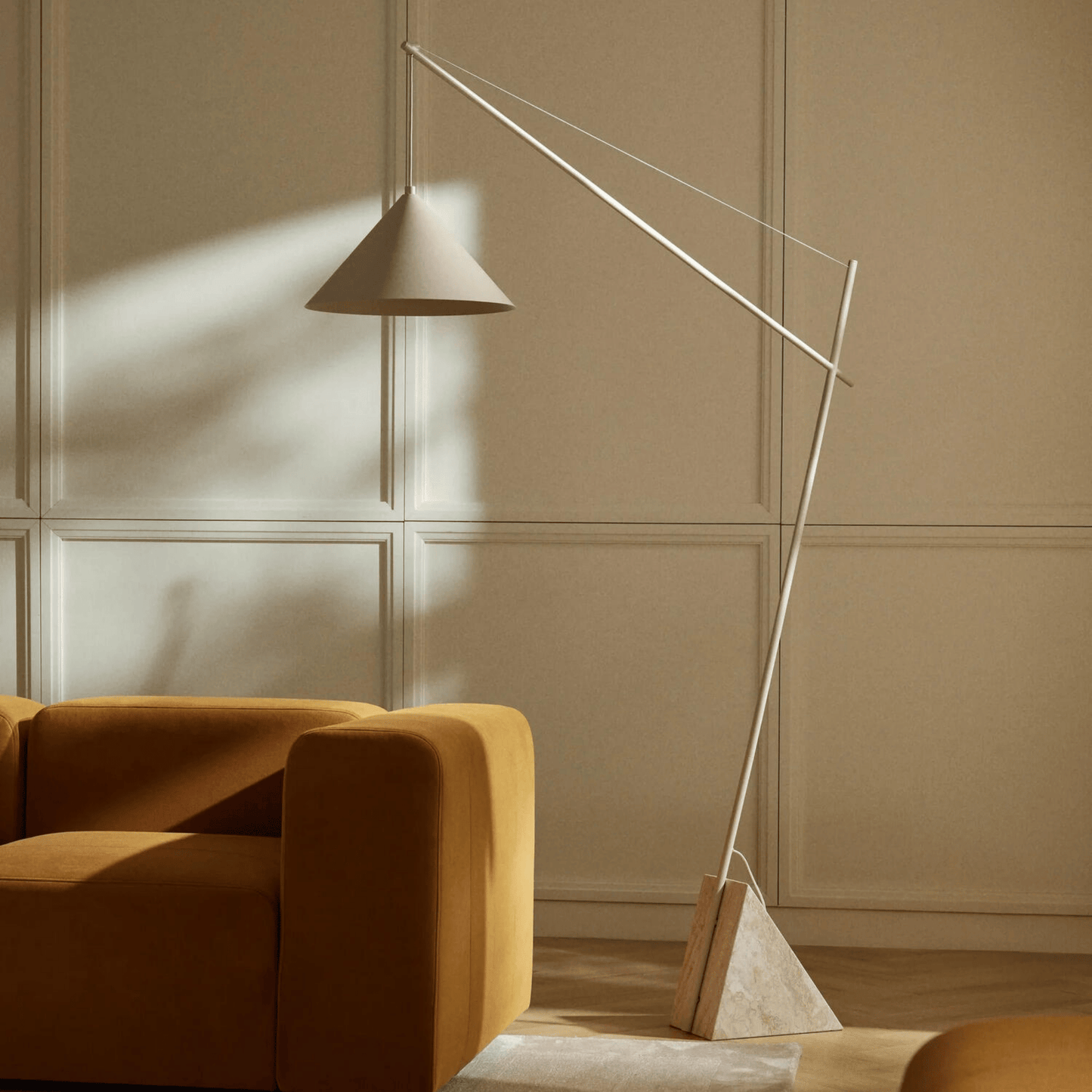 Modern floor lamp next to a brown sofa in a room with beige walls.
