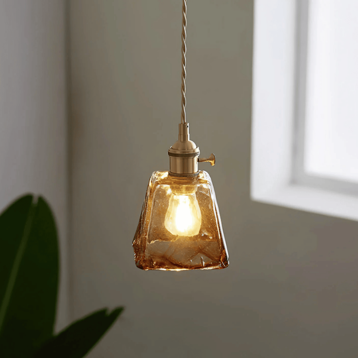 Glass pendant light with a warm glow against a neutral background
