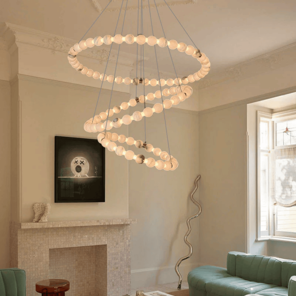 Modern chandelier in a living room with a fireplace and green sofa.