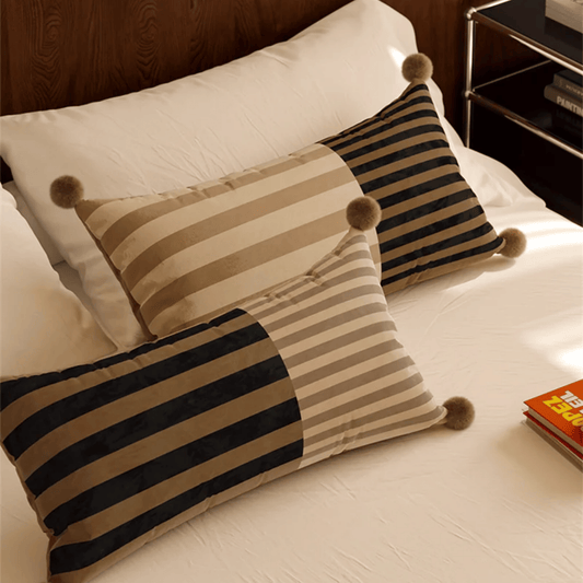 Striped pillows with pom-poms on a bed