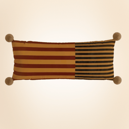 Striped pillow with pom-pom ends on a beige background
