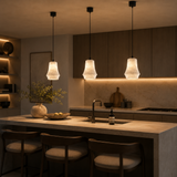 Modern kitchen with pendant lights, island, and bar stools in a warm setting.