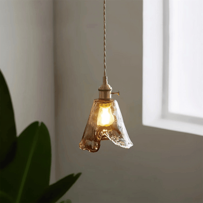 Glass pendant light hanging in a room with a window and plant
