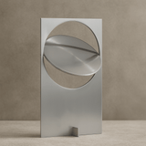 Modern metallic sculpture with geometric design on a neutral background