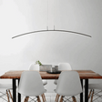 Dining area with a wooden table and white chairs under a modern pendant light.