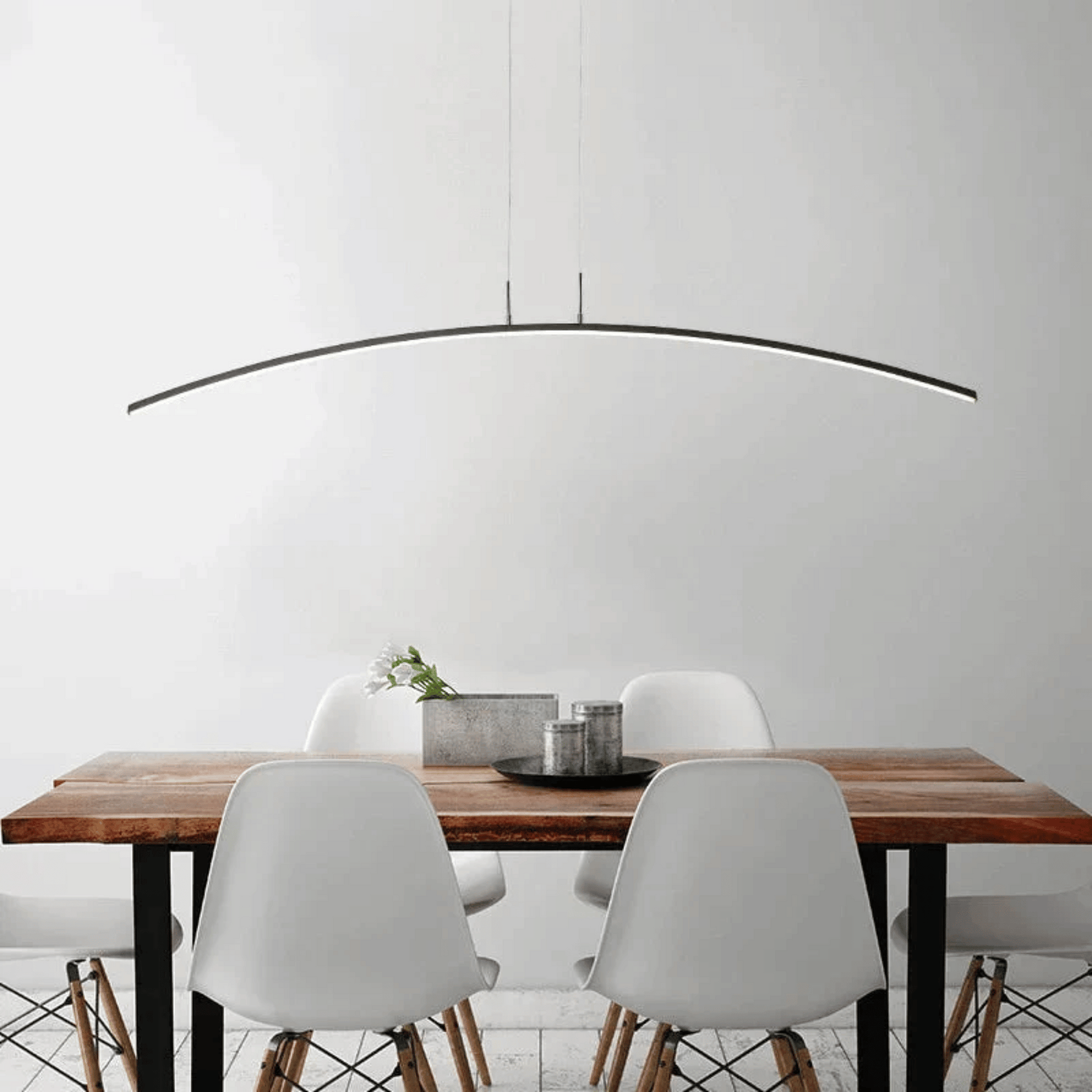 Dining area with a wooden table and white chairs under a modern pendant light.