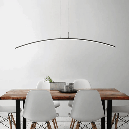 Dining area with a wooden table and white chairs under a modern pendant light.
