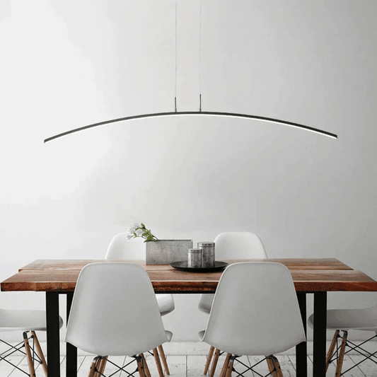 Dining area with a wooden table and white chairs under a modern pendant light.