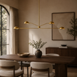 Modern dining room with a gold chandelier, wooden table, and neutral decor.