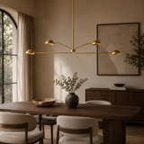 Modern dining room with a gold chandelier, wooden table, and neutral decor.