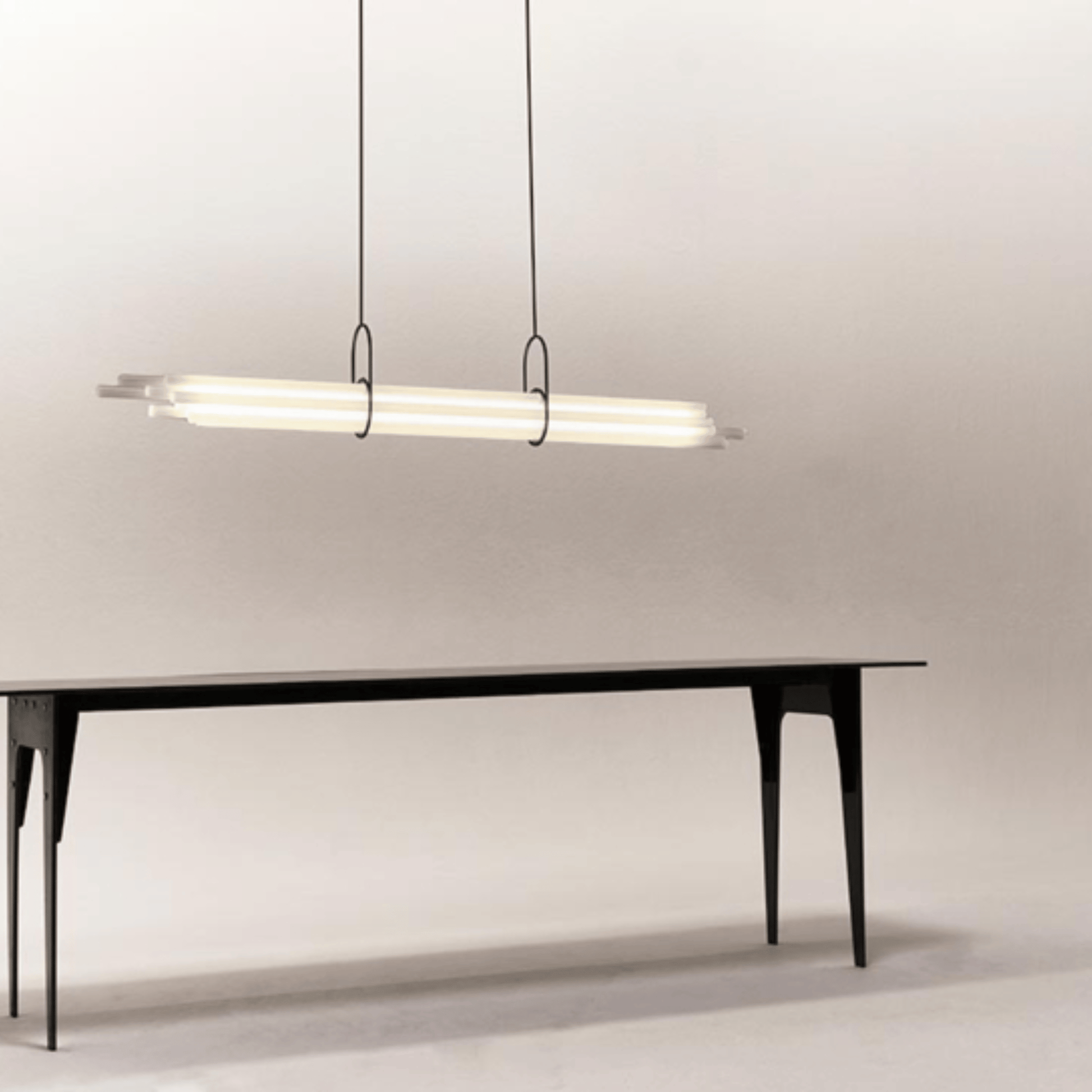Modern black dining table with a linear pendant light on a neutral background