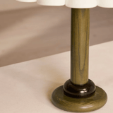 Close-up of a table lamp with a wooden base and white shade on a beige surface.