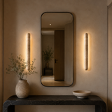 Modern interior with a mirror, wall lights, and decorative items on a console table.