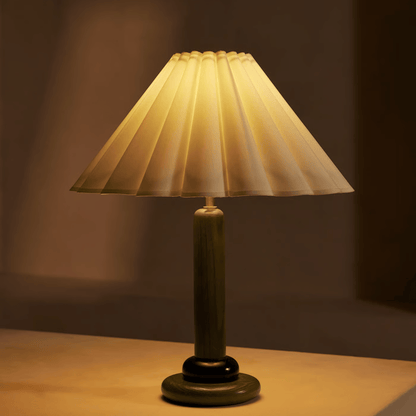 Vintage-style table lamp with pleated shade on a wooden surface.