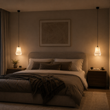 Cozy bedroom with a bed, nightstands, and wall art in warm lighting.